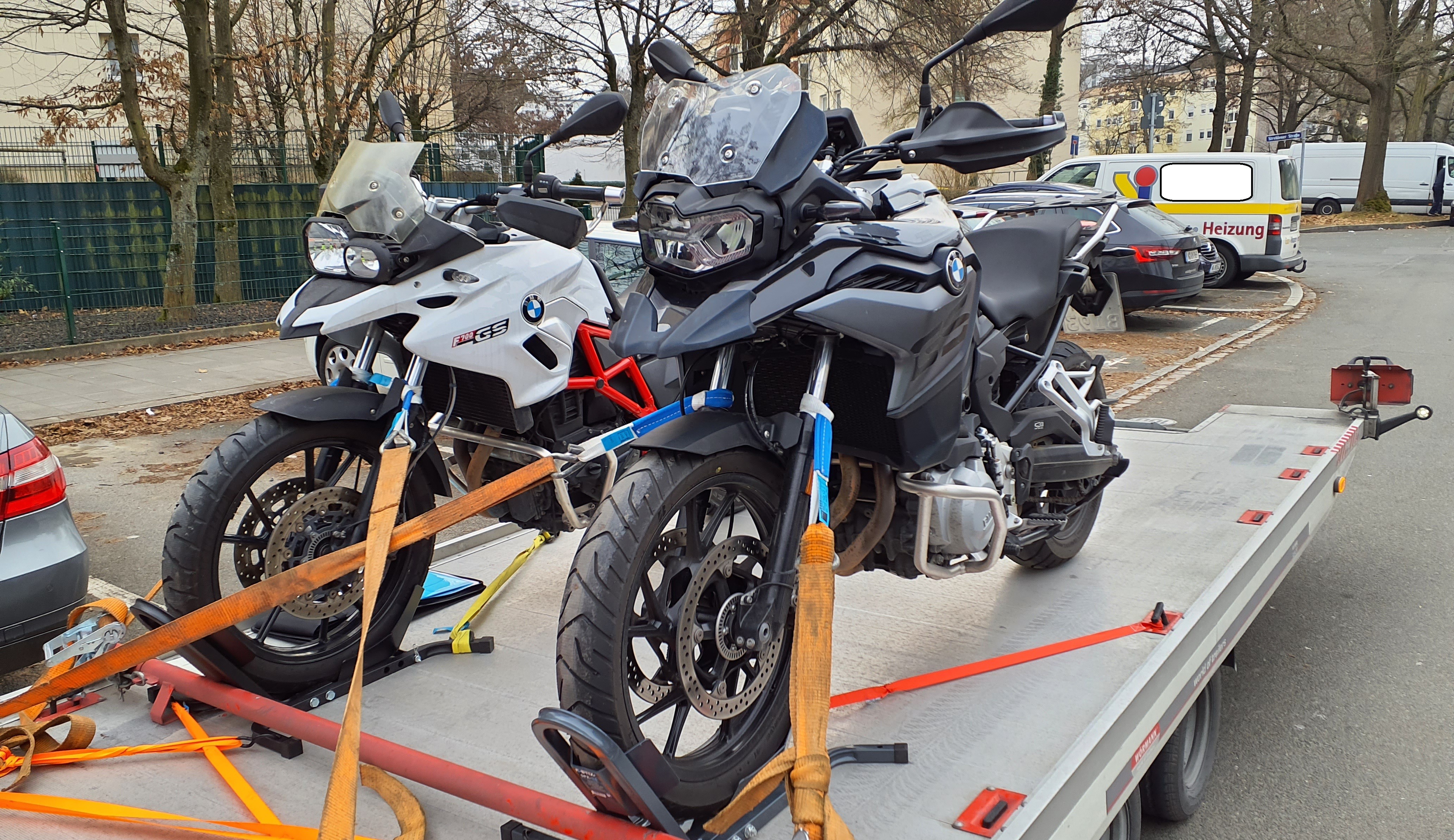 Zwei Motorräder, ein weißes und ein schwarzes, auf einem Transportanhänger.
