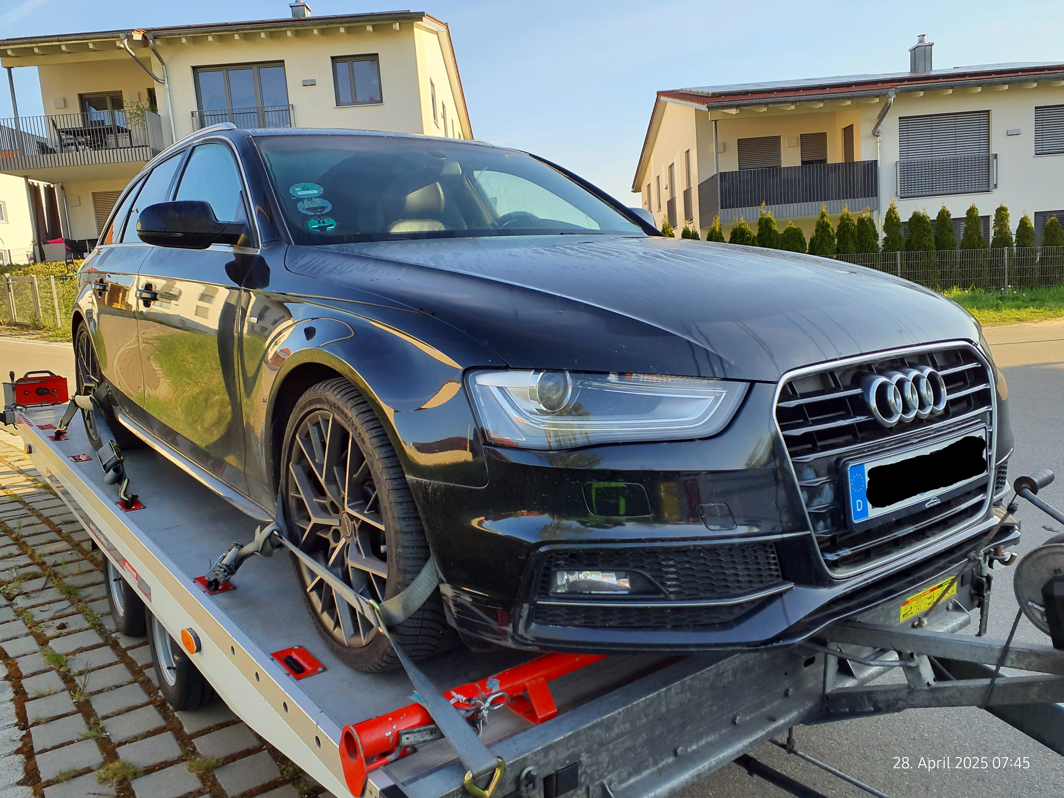 Ein schwarzer Audi wird auf einem Anhänger transportiert in einer gewöhnlichen Nachbarschaft.