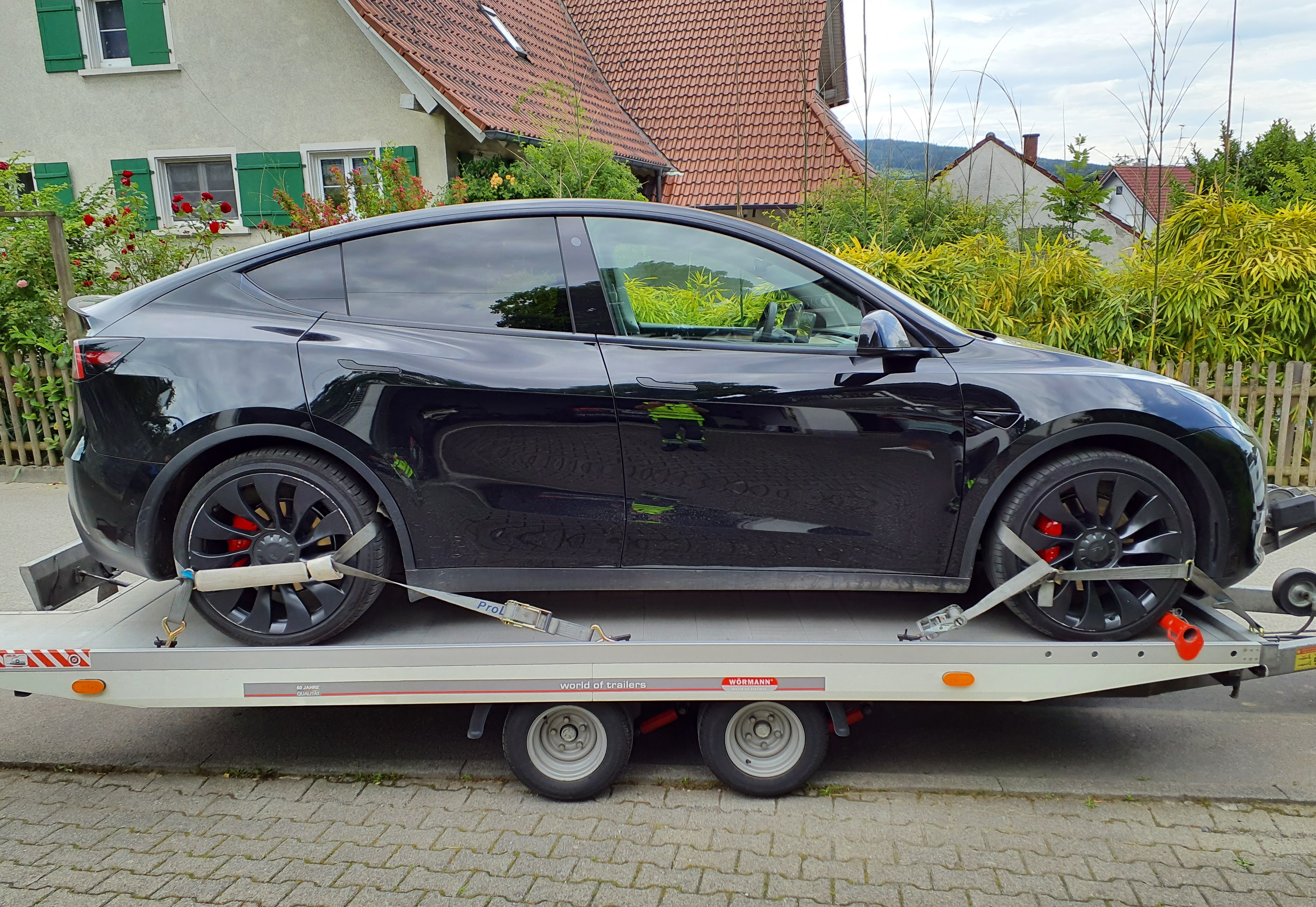 Ein schwarzer SUV von der Seite, auf einem Anhänger befestigt.